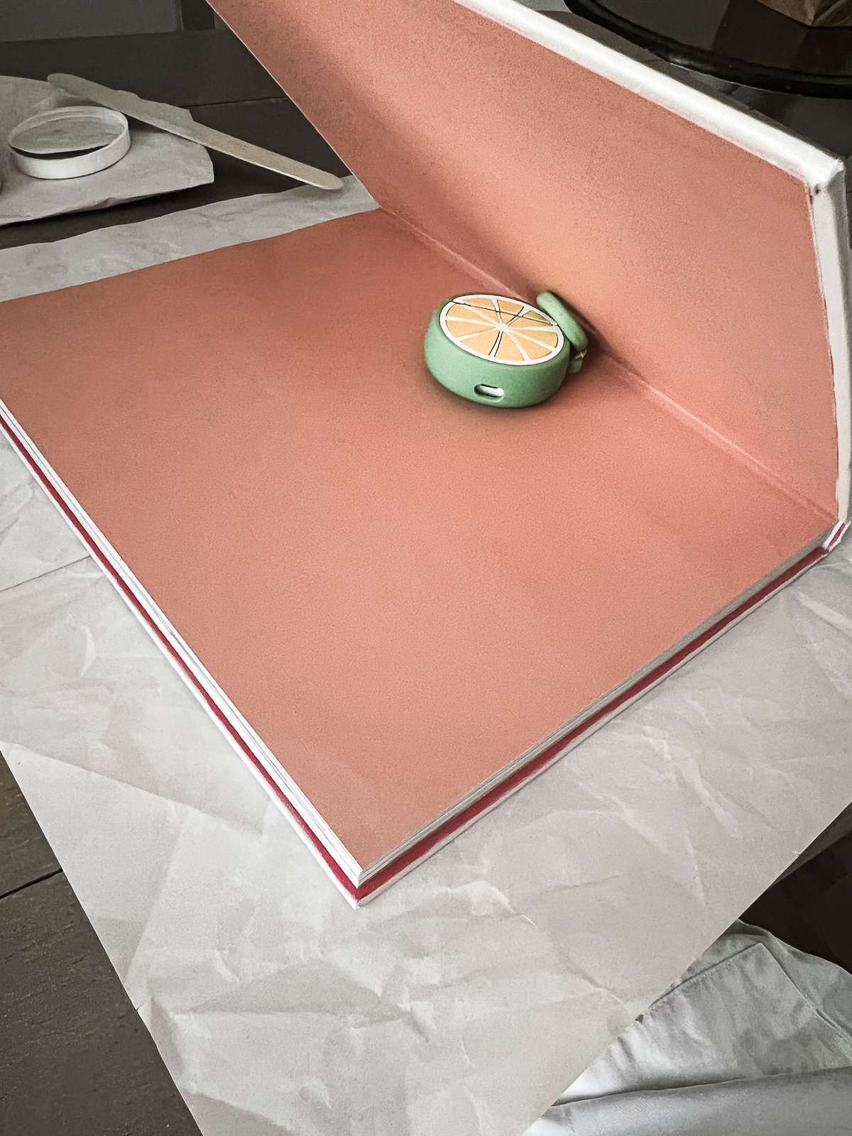 a book being propped open by an air pods case so that the cover can be painted