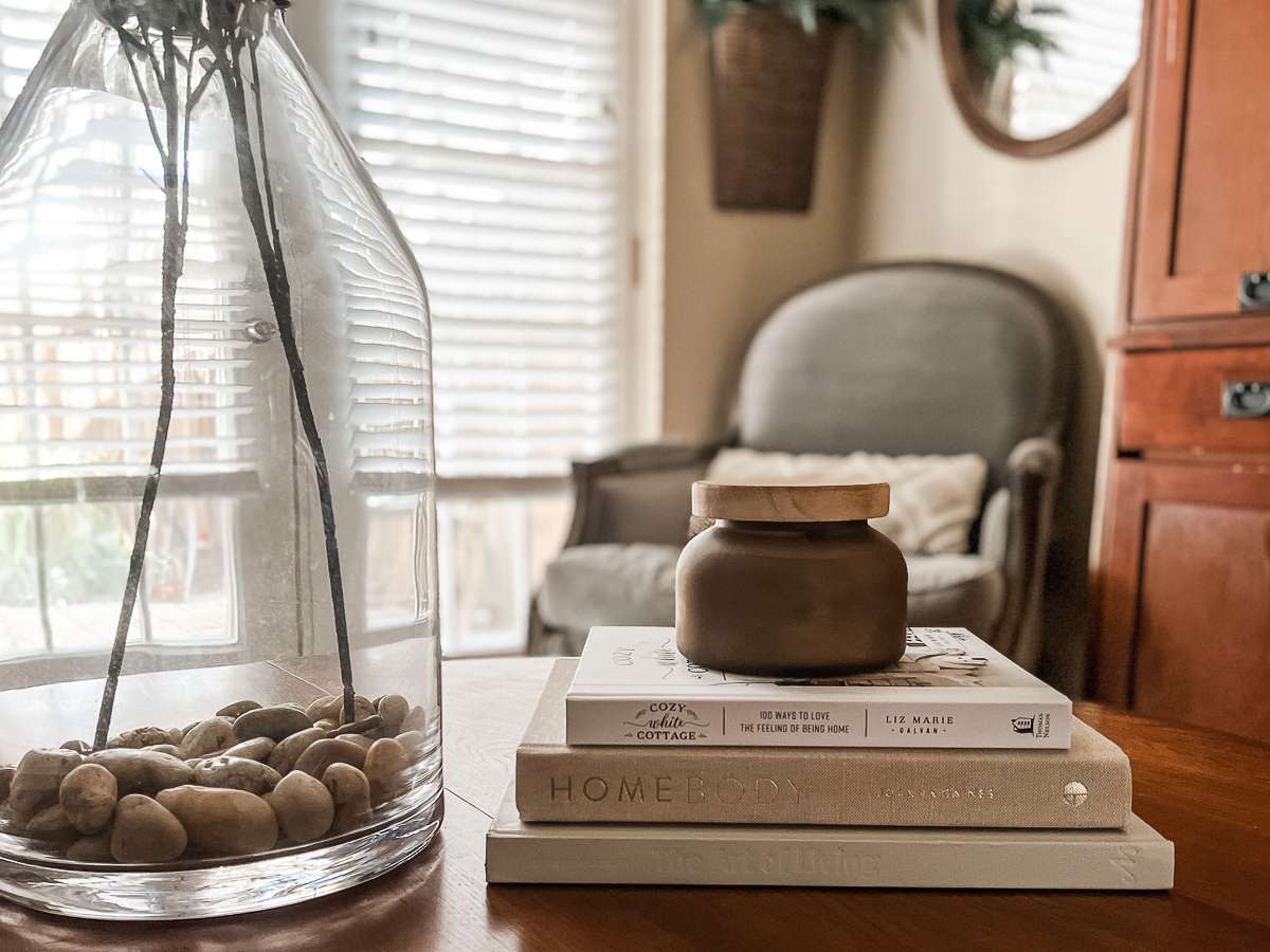 stack of three neutral colored books on a coffee table with a candle on top